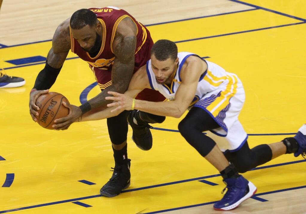 Golden State Warriors guard Stephen Curry and Cleveland Cavaliers forward LeBron James go after a loose ball, during their game in Oakland on Monday, January 16. The Warriors defeated the Cavaliers 126-91.(Christopher Chung/ The Press Democrat)