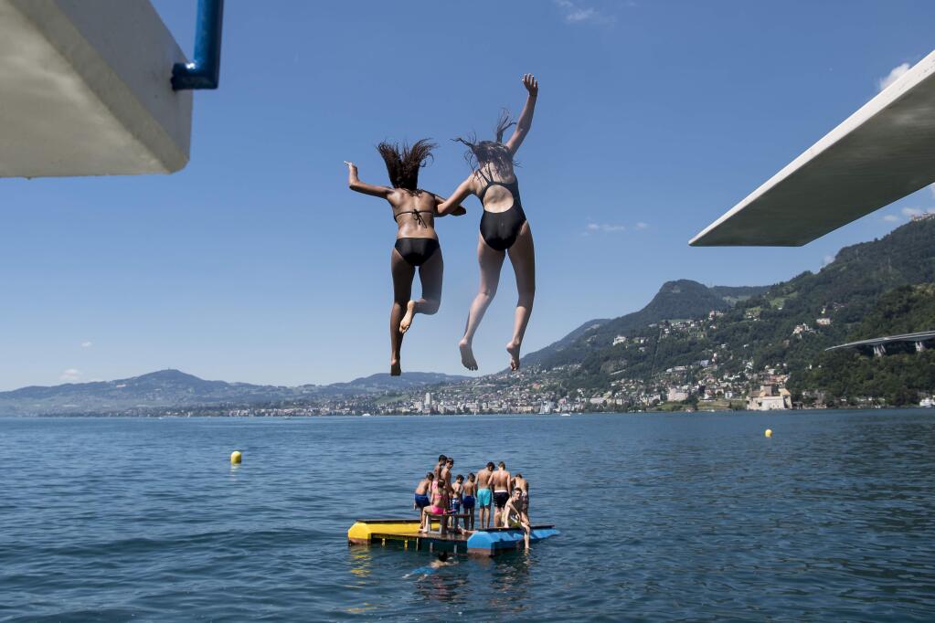 FILE - In this July 9, 2016 file photo, girls jump from a diving platform into the Geneva Lake and enjoy sunny and warm weather, in Villeneuve, Switzerland. After nearly 90 years, women can legally swim topless in Geneva's lake and Rhone River without running the risk of a fine. Geneva's regional council has voted to modify a 1929 ordinance that banned women from swimming topless in the city's main natural waterways, though the change doesn't apply to public swimming pools or swimming totally naked. Nicolas Bolle, an official with Geneva's security department, on Thursday, April 6, 2017 confirmed the council's action a day earlier. (Jean-Christophe Bott/Keystone via AP,file)