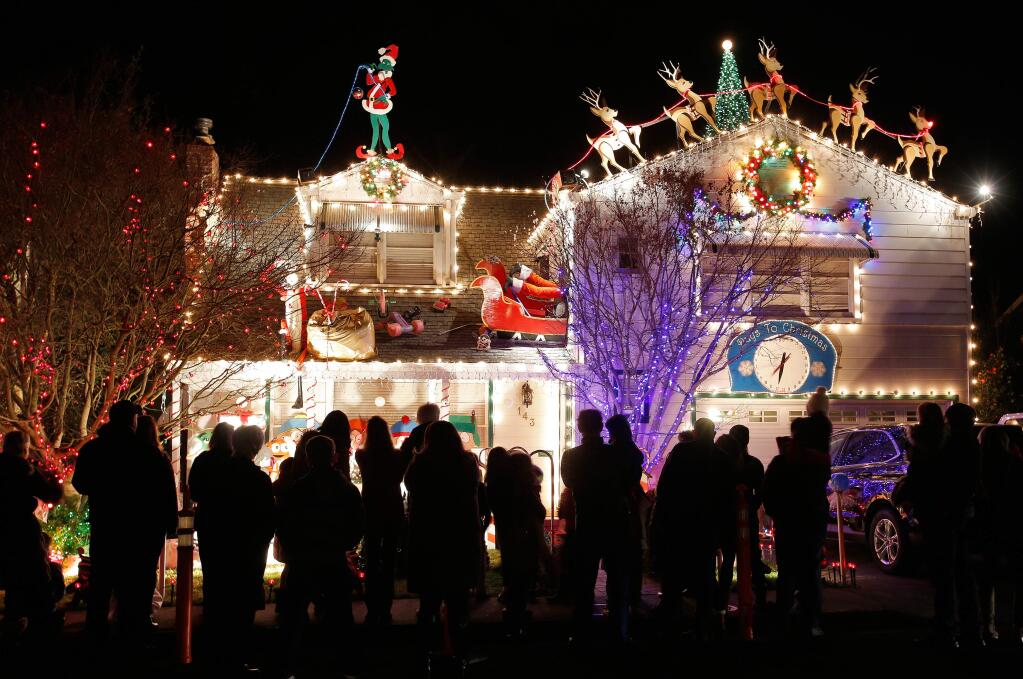 Visitors to Walnut Court stand in front of a house to watch a Christmas light display sychronized to music, in Santa Rosa, California on Wednesday, December 13, 2017. (Alvin Jornada / The Press Democrat)