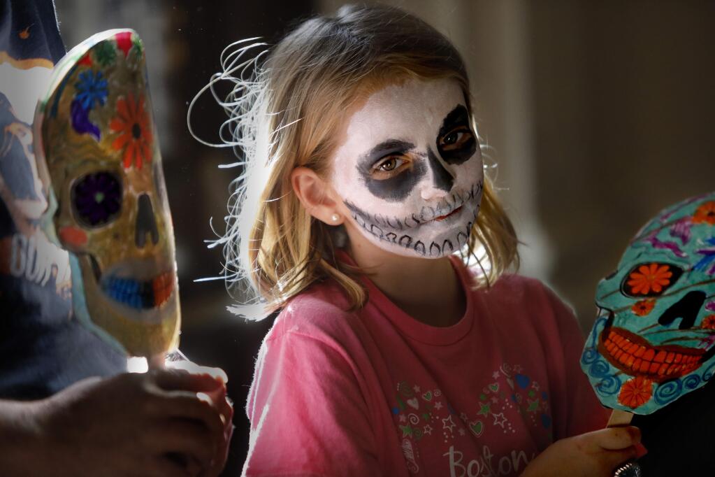 Emilie Frost, 9, watches as her sister Moira, 9, gets her face painted during the Dia de los Muertos family day at the Sonoma County History Museum in Santa Rosa, California on Sunday, October 21, 2018 (BETH SCHLANKER/The Press Democrat)