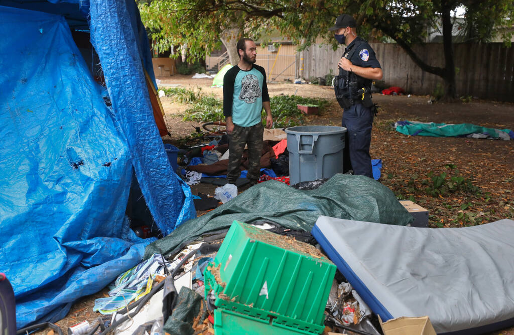 Santa Rosa Police Officer Ryan Cadaret, right, talks to James Hover about moving his encampment at Fremont Park in Santa Rosa on Wednesday, July 29, 2020. Homeless encampments were moved from the western area of the park to mitigate fire risk. (Christopher Chung / The Press Democrat)