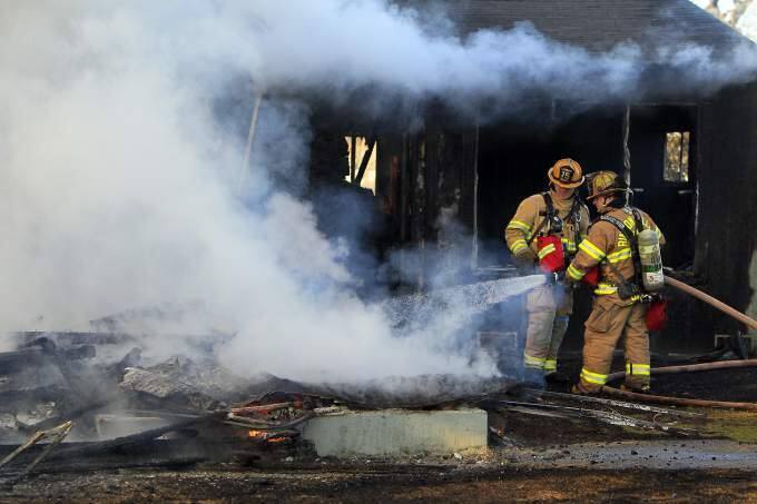 Rincon Valley firefighter Al Baptist, right, and Shawn Johnson hose down the remains of a house fire in Santa Rosa in 2012. (JOHN BURGESS/ PD FILE)