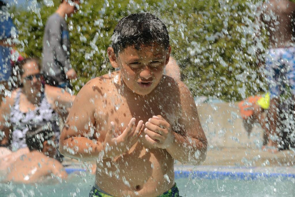 Rodrigo Flores, 10, cools off in the children's play area at Ridgway Swim Center in Santa Rosa on Sunday, June 18, 2017. (ERIK CASTRO/ FOR THE PD)