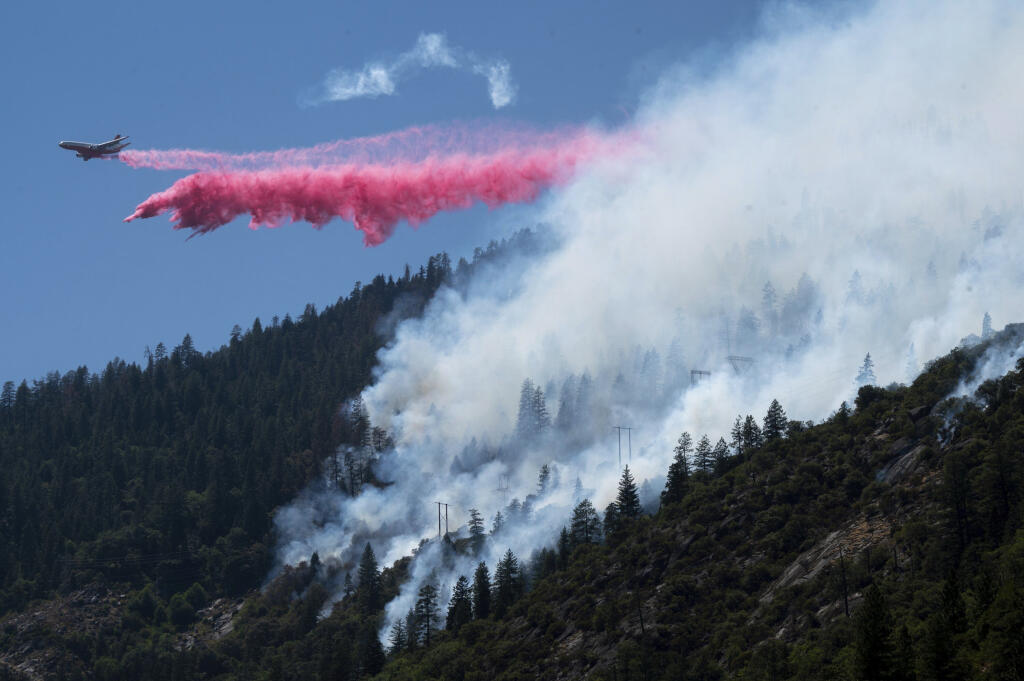 Air tanker drops fire retardant to battle the Dixie Fire in the Feather River Canyon in Plumas County, Calif. on Wednesday, July 14, 2021. Residents were warned to be ready to evacuate as a growing wildfire bears down on two remote Northern California communities near a town largely destroyed by a deadly blaze three years ago. The fire that broke out Tuesday afternoon has chewed through more than 1.8 square miles (4.8 square kilometers) of brush and timber near the Feather River Canyon area of Butte County. (Paul Kitagaki Jr./Sacramento Bee via AP)
