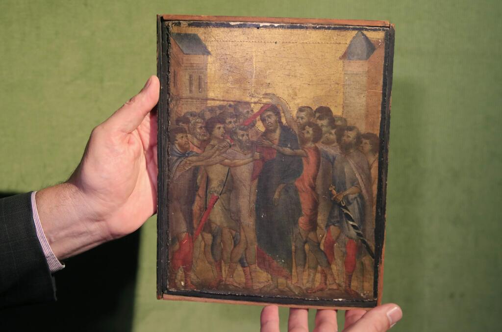 Art expert Stephane Pinta points to a 13th century painting by Italian master Cimabue in Paris, Tuesday, Sept. 24, 2019. A rare 13th century painting by Italian master Cimabue has been found in a French kitchen, and is now expected to fetch millions of euros at an upcoming auction. (AP Photo/Michel Euler)