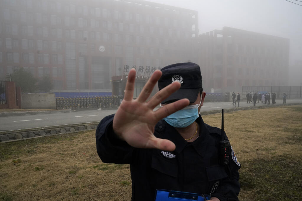 FILE - A security person moves journalists away from the Wuhan Institute of Virology after a World Health Organization team arrived for a field visit in Wuhan in China's Hubei province on Feb. 3, 2021.  (AP Photo/Ng Han Guan, File)