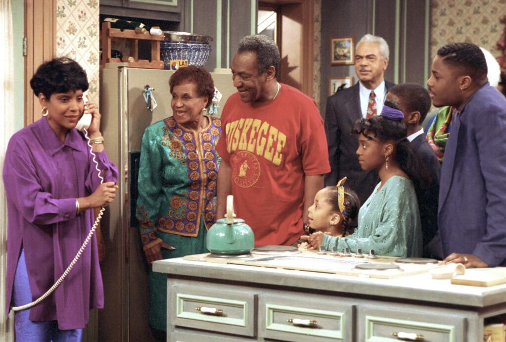 FILE - In this March 6, 1992, file photo, Phylicia Rashad, as Clair Huxtable, talks on the telephone while Bill Cosby, as Dr. Cliff Huxtable, center, and other cast members of the family sitcom 'The Cosby Show,' gather around during taping of the final episode in New York. Bounce TV announced Nov. 11, 2016, that it would resume airing reruns of 'The Cosby Show' on Dec. 19. (AP Photo, File)