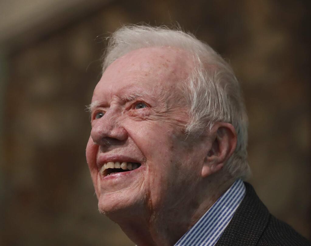 FILE - In this June 9, 2019 file photo, former President Jimmy Carter smiles as he returns to Maranatha Baptist Church to teach Sunday School, less than a month after falling and breaking his hip, in Plains Ga. A guitar signed by the Rolling Stones, vacations to Hawaii, France and Martha's Vineyard and signed photographs of five U.S. presidents are among the items Carter will be auctioning off at his foundation's annual charity benefit. The Carter Center's auction will take place Saturday, June 29, as part of a five-day retreat at a Virginia resort for the Center's supporters. Proceeds will go toward efforts to advance global peace and health care. (Curtis Compton/Atlanta Journal-Constitution via AP, File)