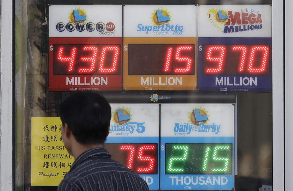 A man walks past Mega Millions and other lottery displays outside of The Lucky Spot in San Francisco, Thursday, Oct. 18, 2018. The Mega Millions jackpot has climbed to $970 million, inching ever-closer to the $1 billion mark. (AP Photo/Jeff Chiu)
