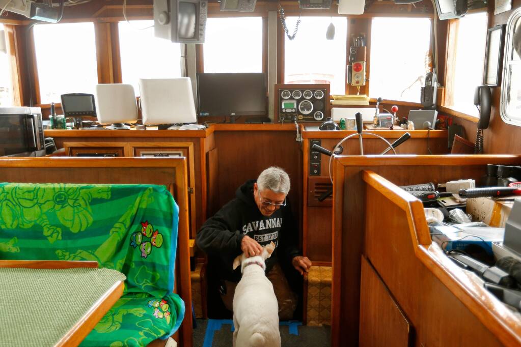 Crab fisherman Dick Ogg is greeted by his dog Buster as he emerges from the engine room of his boat the Karen Jeanne at Spud Point Marina in Bodega Bay, California, on Saturday, November 26, 2016. North Coast fishermen brace for another tough year after state officials announced another delay to commercial crab fishing off the Sonoma and Mendocino County coasts. (Alvin Jornada / The Press Democrat)