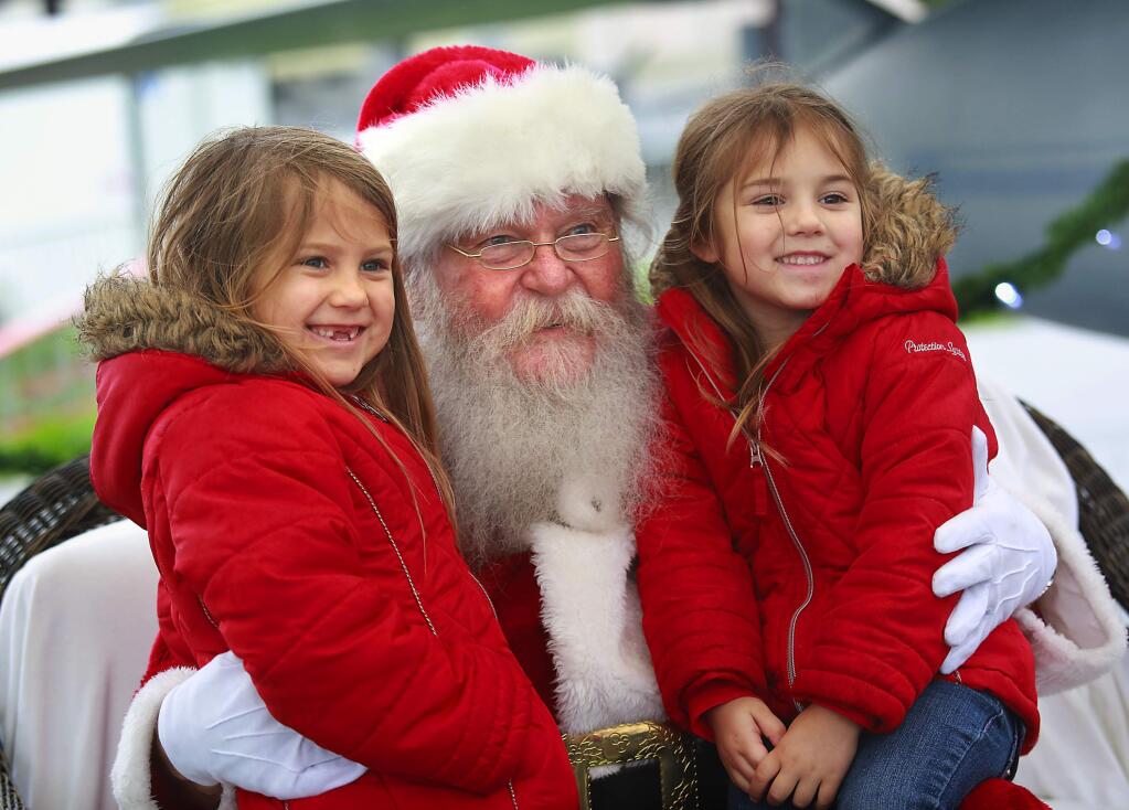 Harper, 6, and sister Kyli Nikol, 4, of Windsor, visit with Santa Claus at the Pacific Coast Air Museum on Saturday, December 20, 2014. (photo by John Burgess/The Press Democrat)