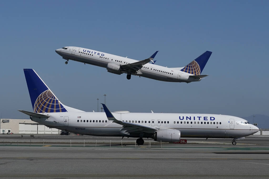 A United Airlines airplane takes off over a plane on the runway at San Francisco International Airport in San Francisco, Thursday, Oct. 15, 2020. (AP Photo/Jeff Chiu)