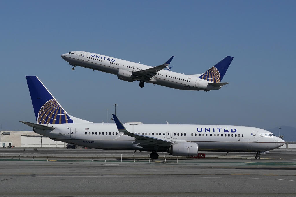 A United Airlines airplane takes off over a plane on the runway at San Francisco International Airport in San Francisco, Thursday, Oct. 15, 2020. (Jeff Chiu / Associated Press)