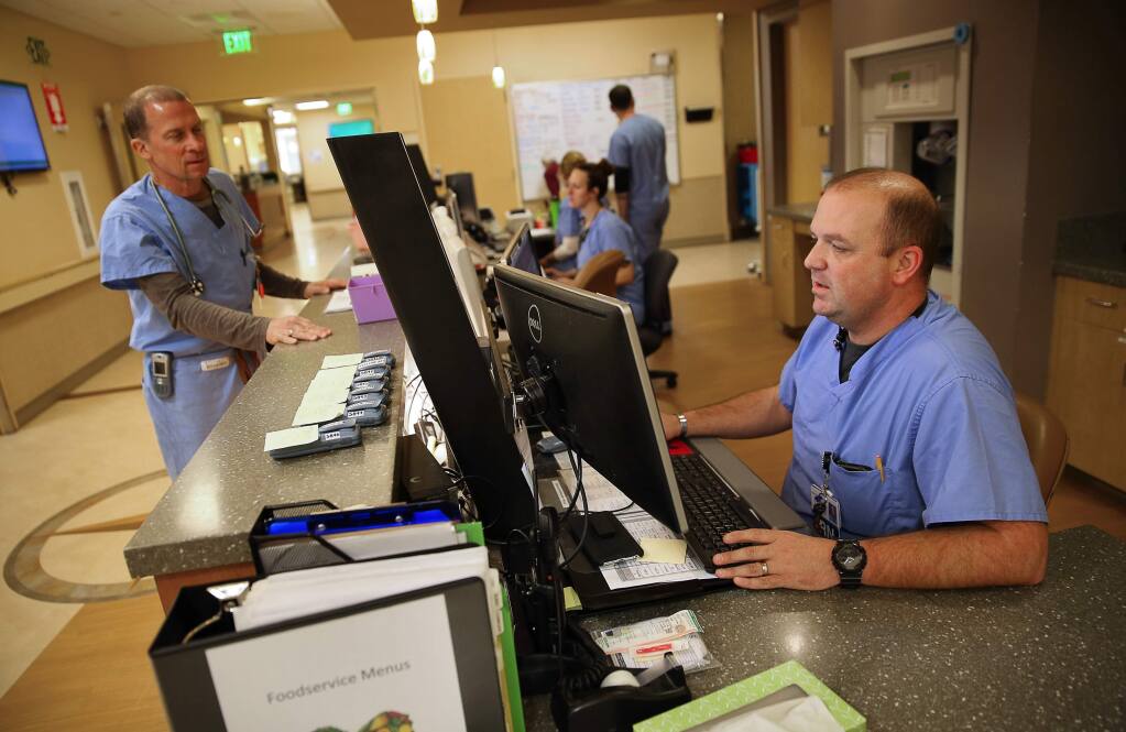 Charge nurse Chad Davis, right, provides information for Dr. Glenn Meade in the Memorial Hospital emergency department in Santa Rosa on Thursday, March 23, 2017. (Christopher Chung/ The Press Democrat)