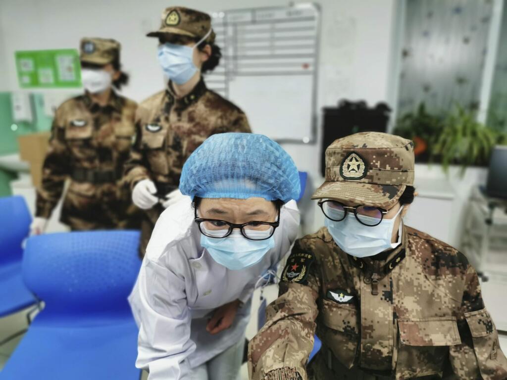 In this Jan. 26, 2020, photo released by Xinhua News Agency, a member of a military medical team takes over the work from a medical worker at Wuhan Jinyintan Hospital in Wuhan, central China's Hubei province. China on Monday expanded sweeping efforts to contain a viral disease by postponing the end of this week's Lunar New Year holiday to keep the public at home and avoid spreading infection. (Li Yun/Xinhua via AP)