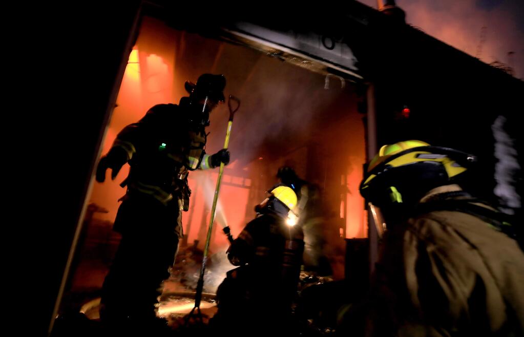 Firefighters prepare to move back to a defensive stance to keep flames from spreading to surrounding vegetation as flames devour a home on Occidental Road near Furlong Road, Tuesday, Oct. 1, 2019. (Kent Porter / The Press Democrat)