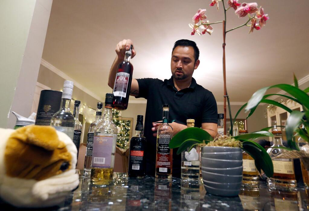 Sal Chavez sets out a variety of liquor bottles for a tasting with his friend and business partner at his home in Sonoma, California, on Wednesday, November 30, 2016. (Alvin Jornada / The Press Democrat)