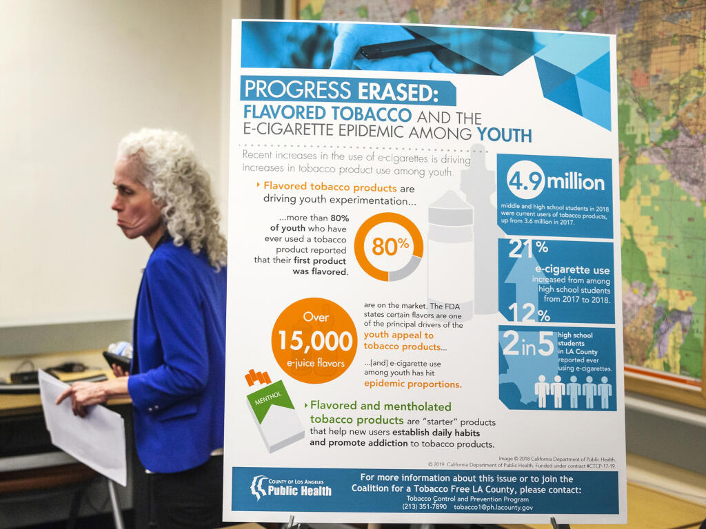 FILE - In this Sept. 6, 2019, file photo, Barbara Ferrer, director of the Los Angeles County Department of Public Health, walks past a poster reading: "Progress Erased: Flavored Tobacco and the e-cigarette epidemic among youth," as the county announced the first known death associated with e-cigarette vaping in Los Angeles. A ballot measure asks voters whether a 2020 law that outlawed the sale of certain flavored tobacco products in California should take effect or be overturned. When the state Legislature passes a law, voters have the power to stop it from ever taking effect if they can gather enough signatures to put a referendum on the ballot. That's what tobacco companies did after lawmakers passed a law in 2020 to outlaw certain flavored tobacco products, arguing the products were designed to appeal to children. The law was delayed until voters could decide in November 2022. (AP Photo/Damian Dovarganes, File)