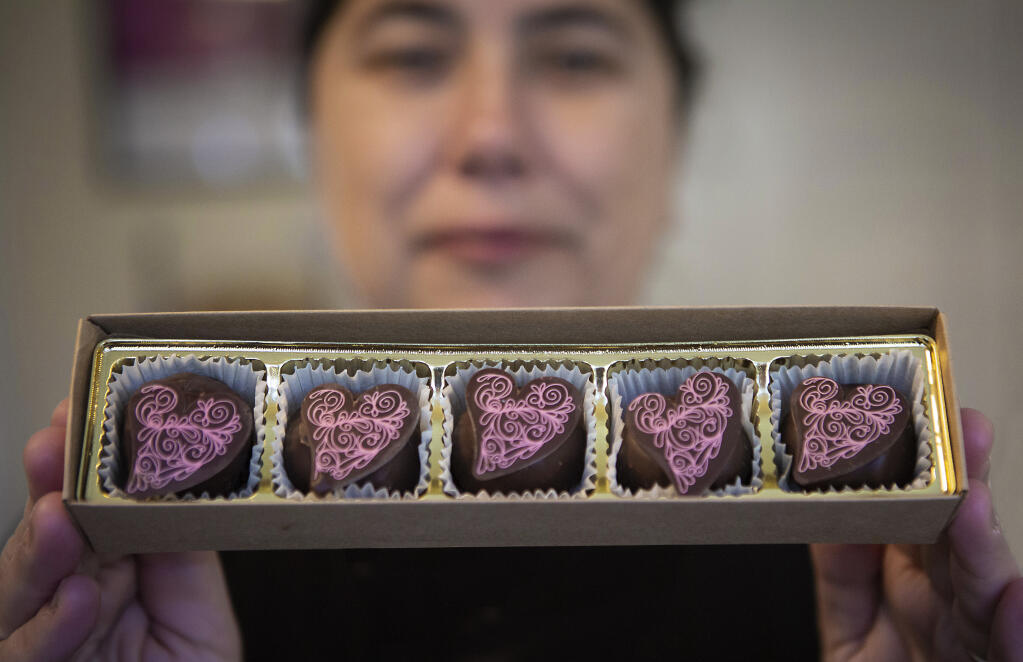 Chocolatier Regina Taormina Rolland, proprietor of the Wine Truffle Boutique, holds a box of handmade wine truffles topped with chocolate swirl hearts in her shop inside the VJB Vineyards and Cellars marketplace in Kenwood on Wednesday, Feb. 8, 2023. (Robbi Pengelly/Index-Tribune)