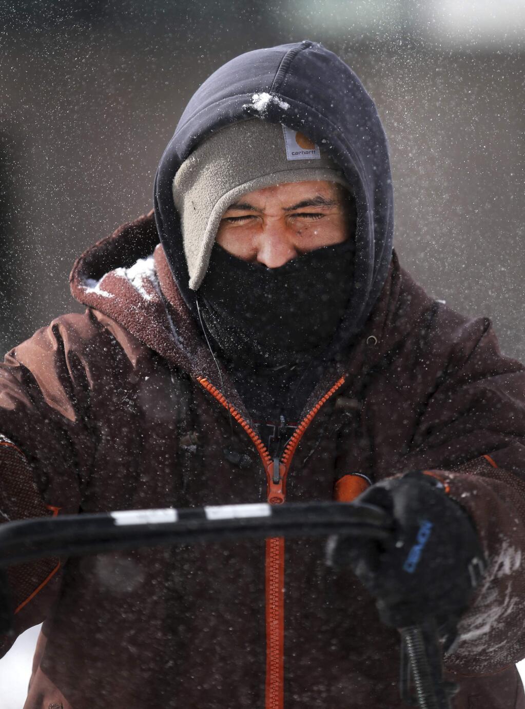 Miguel Honderez braves the cold to clear a sidewalk in the aftermath of a snowstorm on Thursday, March 14, 2019, in Cheyenne, Wyo. According to the National Weather Service, 14.6 inches of snow fell on the city, with maximum wind speeds clocking above 60 miles per hour. (Jacob Byk/The Wyoming Tribune Eagle via AP)