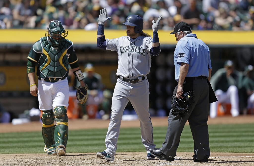 The Seattle Mariners' Taylor Motter, center, celebrates after hitting a grand slam off the Oakland Athletics' Andrew Triggs in the third inning Sunday, April 23, 2017, in Oakland. At left is A's catcher Stephen Vogt, at right is home plate umpire Tom Hallion. (AP Photo/Ben Margot)
