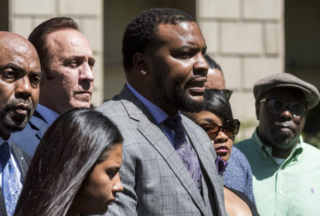 Lee Merritt, center, leads a news conference, Monday, April 23 2018, in San Bernardino, Calif., announcing a series of lawsuits against the Barstow Police Department regarding the shooting death of Diante 'Butchie' Yarber. Family members and attorneys are disputing the official account of the fatal police shooting of Yarber, a 26-year-old black man, during a traffic stop earlier in the month in Barstow, Calif. (James Quigg/The Daily Press via AP)