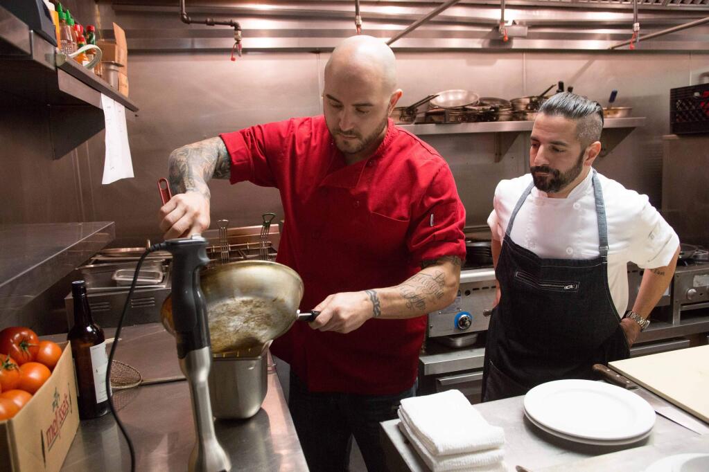 In this January 2015 photo provided by FYI Network, Mark Cammarano, left, owner and chef of Cammarano's American Fusion restaurant in Simi Valley, Calif, cooks with FYI's 'Say It To My Face!' co-host Anthony Dispensa, right, in the kitchen. The traditional restaurant review is being drowned out by a chorus of Instagram photos, Yelp rants and blog posts on each and any dinner served. In the new show Say It To My Face!' chefs and online critics hash it out, opening a fiery debate on new medias role in a restaurants success. (Richard Knapp/FYI Network via AP)