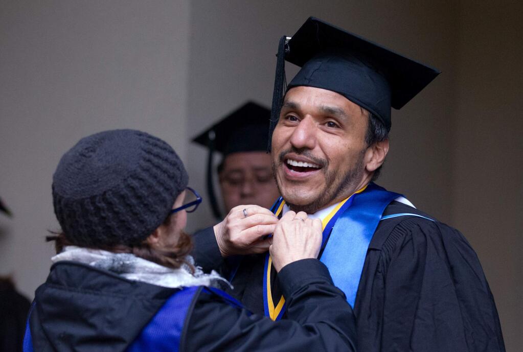 Harold Pleitez of Los Angeles, gets an adjustment from a friend as he waits before receiving his Masters degree before SSU's commencement ceremony for the School of Arts and Humanities, in Rohnert Park on Saturday, May 18, 2019. (Photo by Darryl Bush / For The Press Democrat)