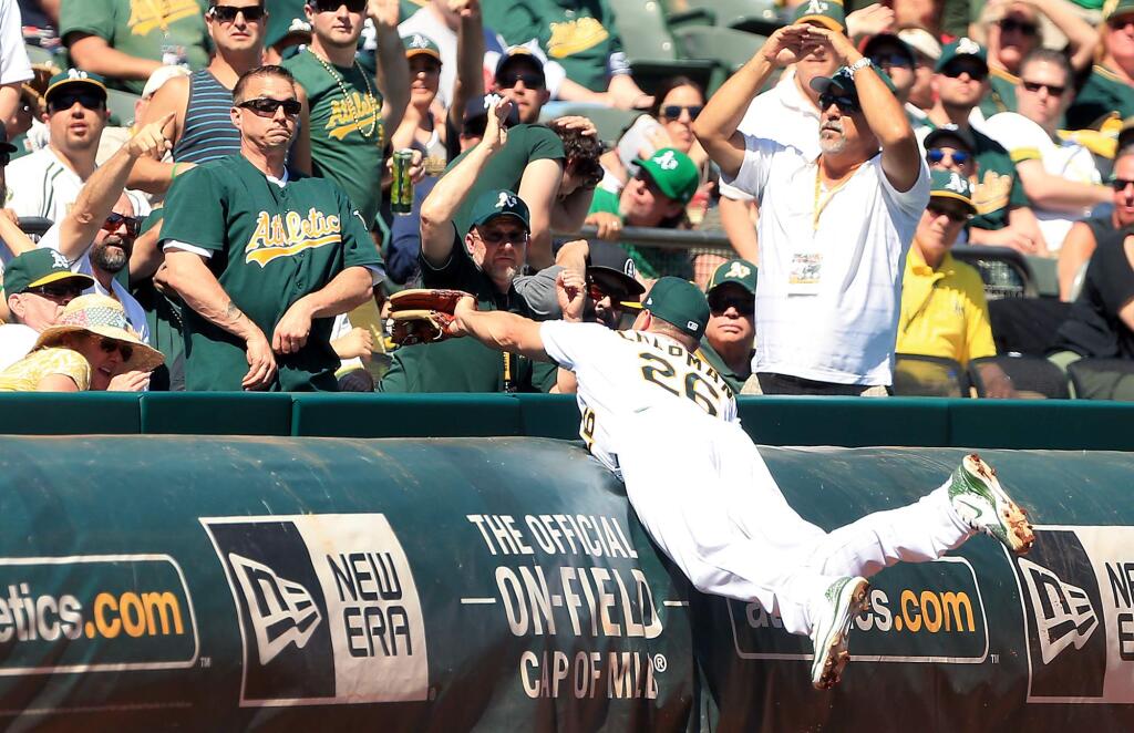 Third baseman Matt Chapman reaches into the stands to make a catch off Angels hitter Luis Valbuena during the second inning of the Athletics' opening-day win against the Angels, Thursday March 29, 2018 in Oakland. (Kent Porter / The Press Democrat)