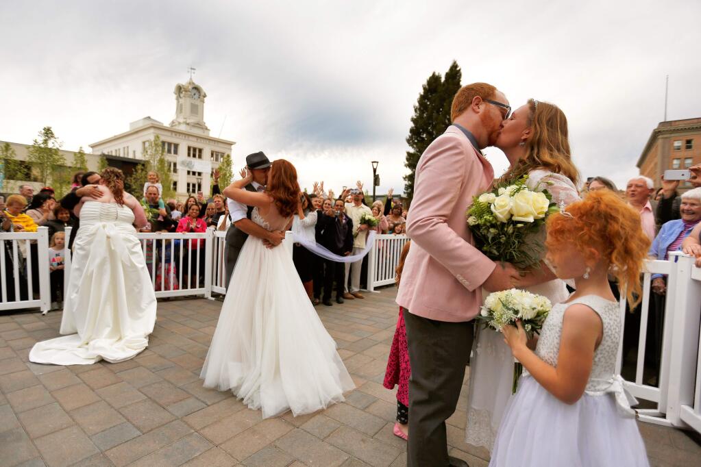Newlywed couples, from right, Larisa Ashley and Noah Gunnell, Amber and Gabe Tansey, and Roxanna and Brandon Ashby kiss their respective spouses at the conclusion of their joint wedding ceremony during the Wednesday Night Market in Santa Rosa, California, on Wednesday, June 7, 2017. (Alvin Jornada / The Press Democrat)
