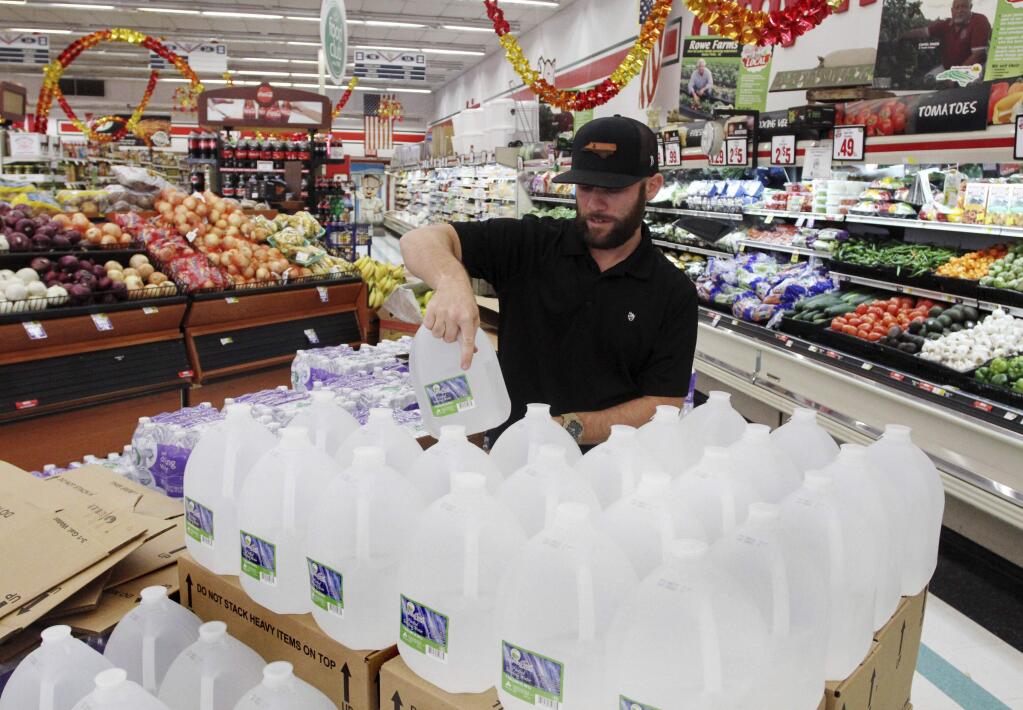 Chris Creel, manager of Piggly Wiggly, stocks pallets of bottled water as grocery customers prepare for the arrival of storm weather with Hurricane Dorian in New Bern, N.C., Wednesday, Sept. 3, 2019. New Bern is still recovering from the damages caused by Hurricane Florence in 2018. (Gray Whitley/Sun Journal via AP)