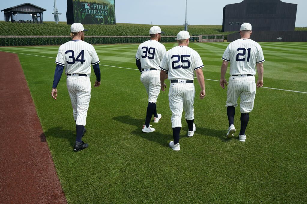 Chicago White Sox players Michael Kopech (34), Aaron Bummer (39), Andrew Vaughn (25) and Zack Collins (21) walk on the field before a baseball game against the New York Yankees, Thursday, Aug. 12, 2021, in Dyersville, Iowa. The Yankees and White Sox are playing at a temporary stadium in the middle of a cornfield at the Field of Dreams movie site, the first Major League Baseball game held in Iowa. (AP Photo/Charlie Neibergall)