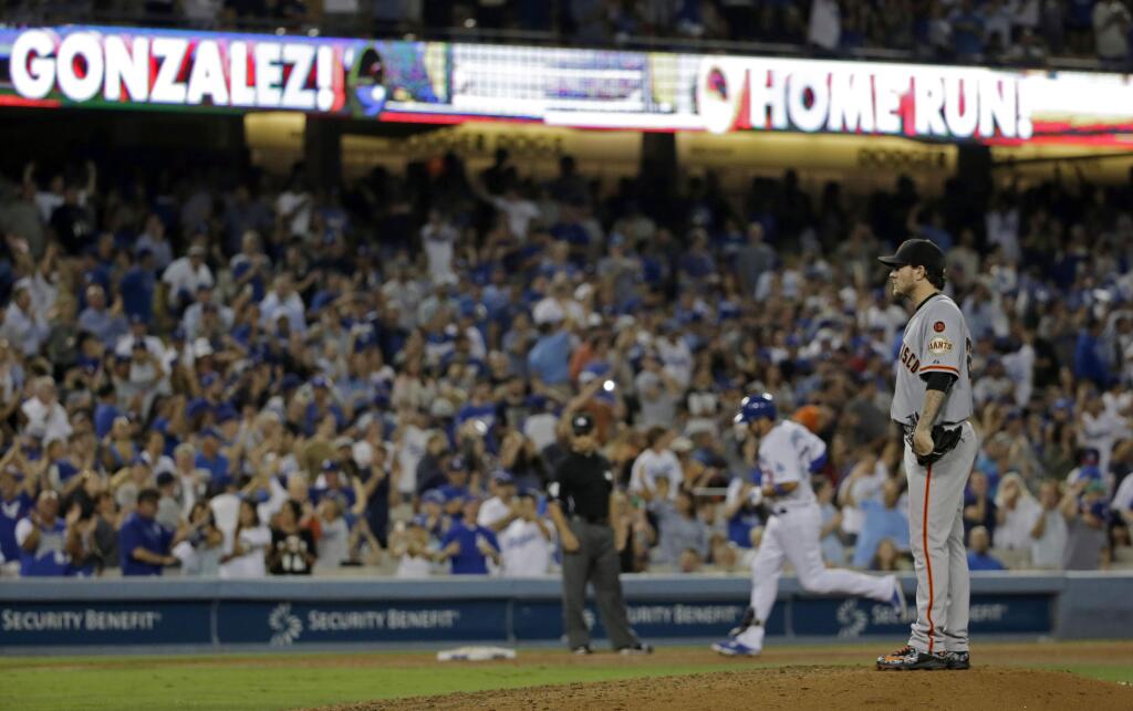 Los Angeles Dodgers' Adrian Gonzalez, back, rounds the bases after a two-run home run as San Francisco Giants starting pitcher Jake Peavy looks away during the sixth inning of a baseball game in Los Angeles, Monday, Aug. 31, 2015. (AP Photo/Chris Carlson)