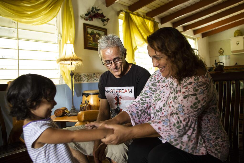 From left, Luana Colón Mendez, 2, Charlie Colón and Jazmín Méndez celebrate after they received power in their home in the Barrio Real Anón neighborhood of Ponce, Puerto Rico, Aug. 14, 2018. Méndez and her family are the last residential Puerto Rico Electric Power Authority customers to regain power since Hurricane Maria hit the island on Sept. 20, 2017. (Erika P. Rodriguez/The New York Times)