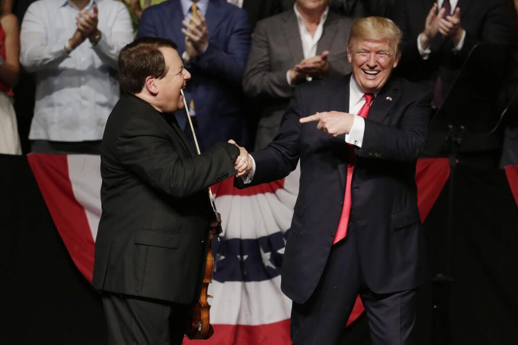 President Donald Trump shakes hands with Cuban violinist Luis Haza after a speech announcing a revised Cuba policy aimed at stopping the flow of U.S. cash to the country's military and security services while maintaining diplomatic relations, Friday, June 16, 2017, in Miami. (AP Photo/Lynne Sladky)