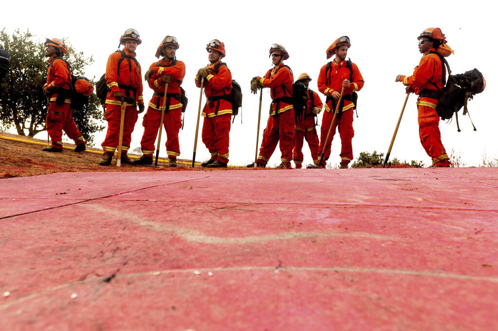 FILE - In this Aug. 17, 2020, file photo, inmate firefighters - notable by their bright orange fire gear compared to the yellow worn by professional firefighters - prepare to take on the River Fire in Salinas, Calif. California could change its constitutional ban on slavery to remove the words "unless for the punishment of crime," further reducing the state's already faltering dependence on thousands of inmate firefighters, under a proposed amendment backed Thursday, Feb. 25, 2021, by local officials and actor-activist Danny Glover. (AP Photo/Noah Berger, File)