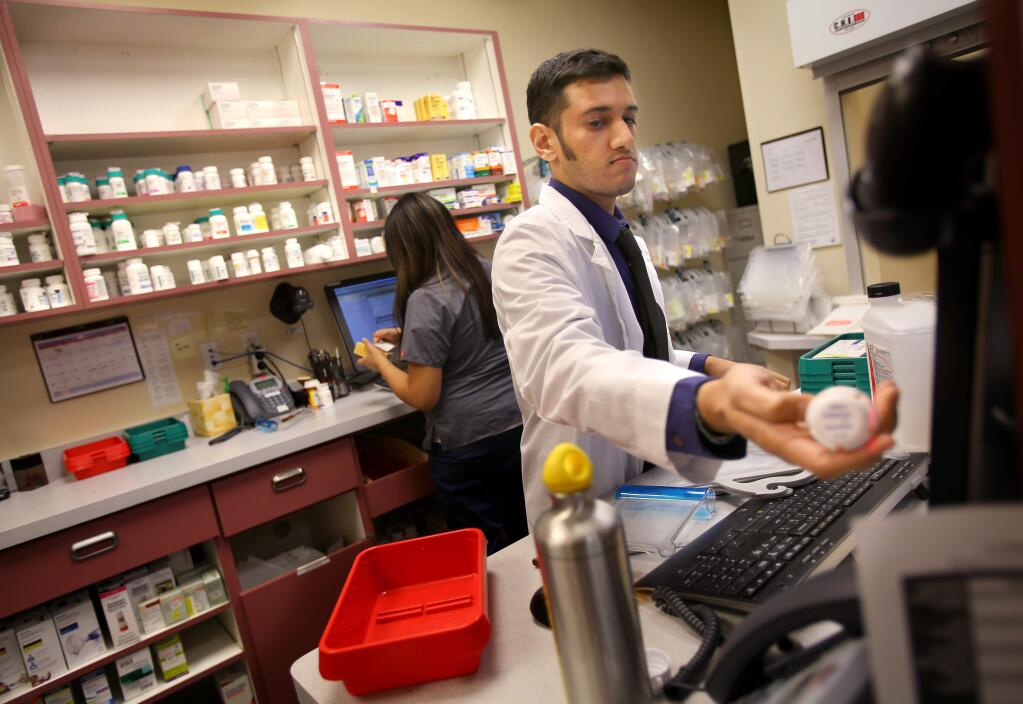 Pharmacist in charge Ash Govind scans a prescription in the Lombardi Pharmacy at the Southwest Community Health Center, in Santa Rosa on Wednesday, December 3, 2014. (Christopher Chung/ The Press Democrat)