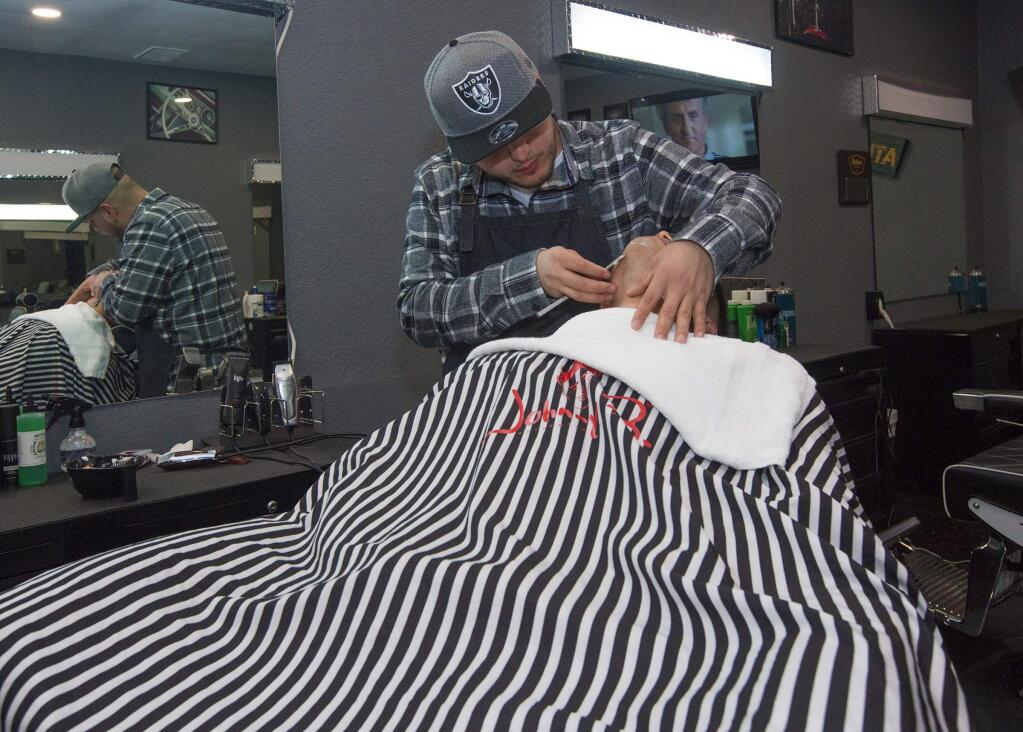 Jose Alvarez, proprietor of Barbers Garage, the new barbershop on Highway 12 in Boyes Hot Springs, gives a straight-razor shave to Mario Carreno. (Photo by Robbi Pengelly/Index-Tribune)