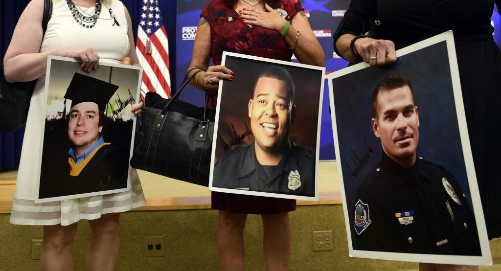 People holding photos arrive for an event with President Donald Trump on the White House complex in Washington, Friday, June 22, 2018, about crime committed by undocumented immigrants. (AP Photo/Susan Walsh)