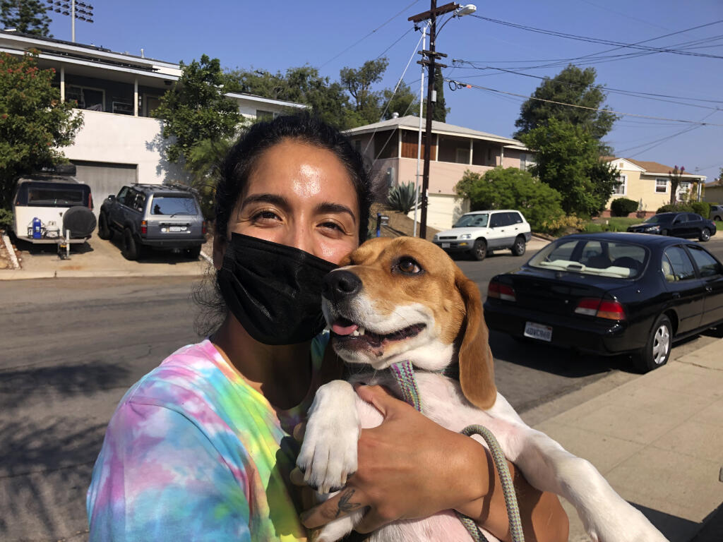 Briana Mendoza, 30, on Tuesday, Sept. 14, 2021, poses with her dog outside a polling site at a San Diego high school. Mendoza said she voted against recalling California Gov. Gavin Newsom. She said the state does not need to replace a governor who has been working to curb the spread of the coronavirus. (AP Photo by Julie Watson)