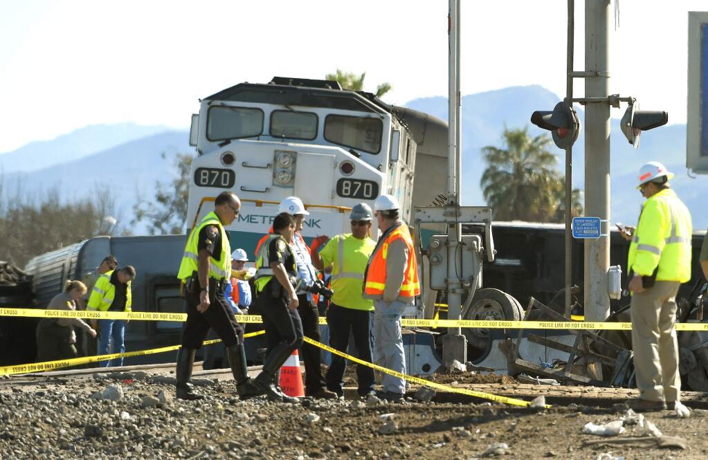 FILE - In this Tuesday, Feb. 24, 2015, file photo, workers stand near a Metrolink train that hit a truck and then derailed in Oxnard, Calif. Police say an engineer injured in last week's California commuter train derailment has died. The Oxnard Police Department says it was notified Tuesday, March 3, 2015 by Cedars-Sinai Medical Center in Los Angeles that 62-year-old Glenn Steele had died. Steele had been transferred to Cedars-Sinai from a hospital in Ventura County. (AP Photo/Mark J. Terrill, File)