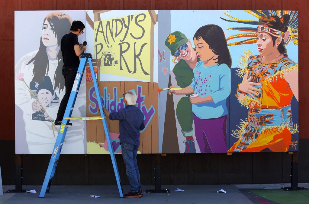 Artists Daniel Doughty and Mario Uribe hang a multi-panel Healing Mural they created honoring the memory of Andy Lopez at the Roseland Village Neighborhood Center on Thursday in preparation for the unveiling on Friday. (John Burgess/The Press Democrat)