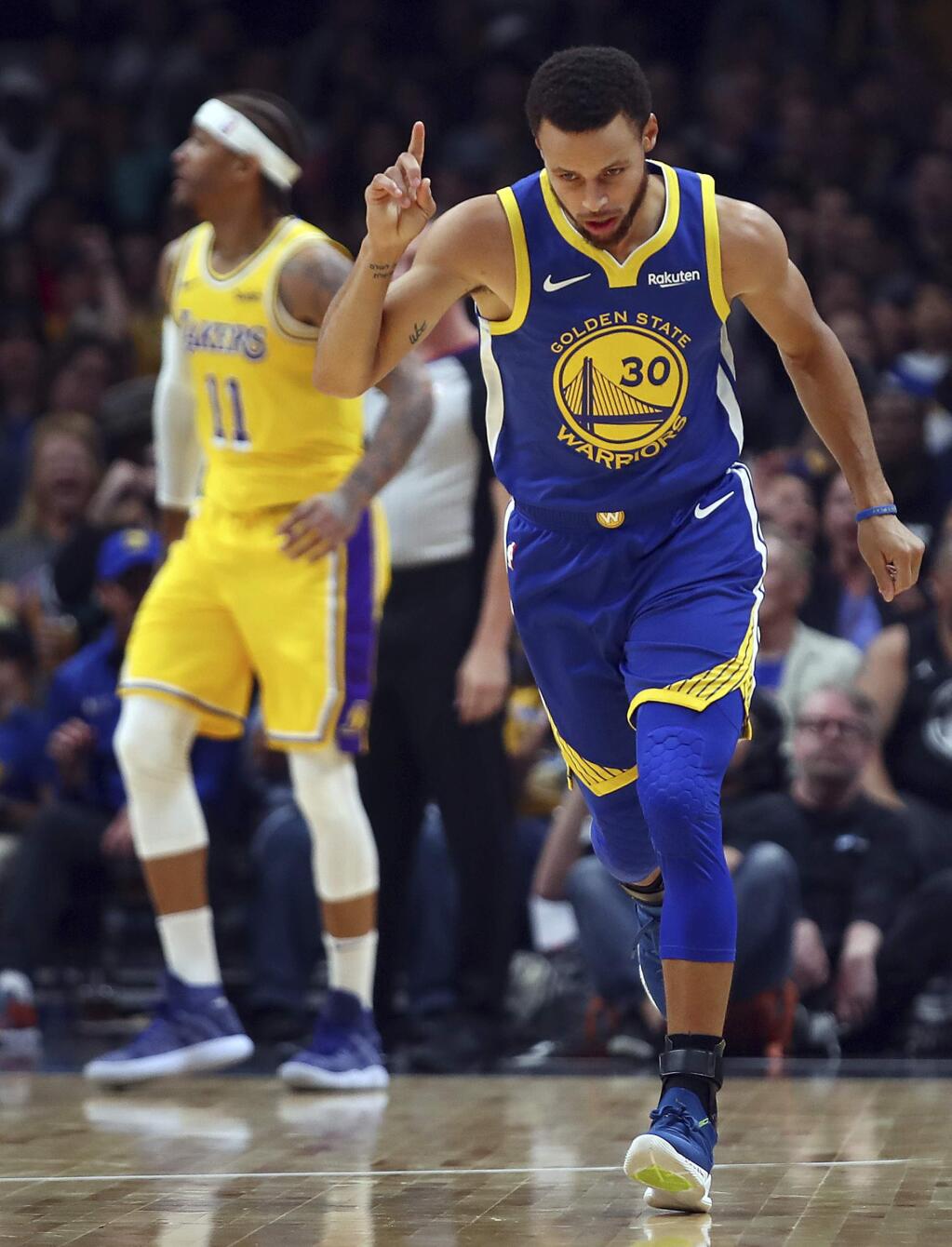 The Golden State Warriors' Stephen Curry, right, celebrates a score against the Los Angeles Lakers during the first half of a preseason game Friday, Oct. 12, 2018, in San Jose. (AP Photo/Ben Margot)