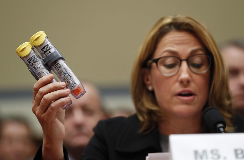 Mylan CEO Heather Bresch holds up an EpiPen while testifying on Capitol Hill in Washington, Wednesday, Sept. 21, 2016, before the House Oversight Committee hearing on EpiPen price increases. Bresch defended the cost for life-saving EpiPens, signaling the company has no plans to lower prices despite a public outcry and questions from skeptical lawmakers. (AP Photo/Pablo Martinez Monsivais)