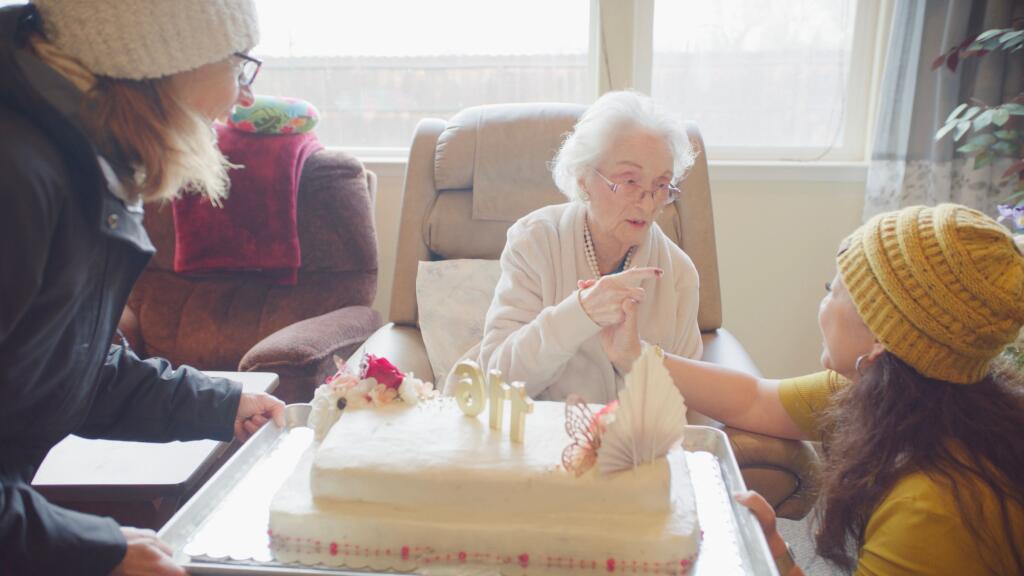Edie Ceccarelli receives a birthday cake from, left, parade coordinator Suzanne Picetti-Johnson, and Perla Gonzalez, co-owner of the Holy Spirit Residential Care Home, at Ceccarelli’s 116th birthday party in Willits, Sunday, Feb. 4, 2024. (Yoni Brook)