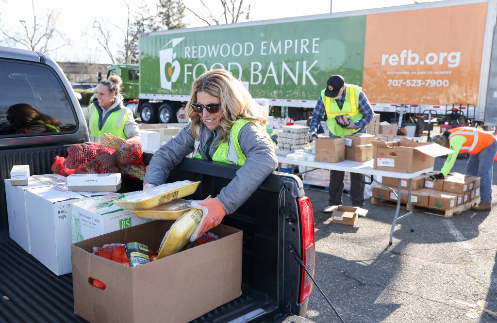 Volunteer Cathy Halverson loads frozen chicken into a truck during a Redwood Empire Food Bank drive-thru and walk-thru distribution event at the Santa Rosa Veterans Memorial Building on Thursday, March 2, 2023.  (Christopher Chung/The Press Democrat)