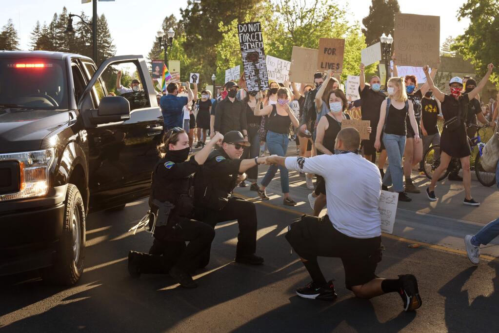 Healdsburg Police officers Kristin Dean, left, and Craig Smith, center, kneel and fist pumped protesters as they made their way around the traffic circle during a George Floyd protest held Thursday in Healdsburg, Calif., on June 4, 2020. (Photo: Erik Castro/for The Press Democrat)