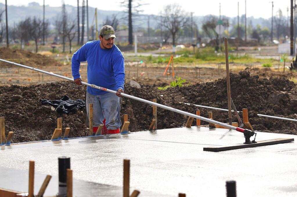 Fabian Leon smooths over the concrete foundation for a home being rebuilt on Randon Way, by Synergy Group by Christopherson, in the Coffey Park neighborhood of Santa Rosa on Friday, May 4, 2018. Synergy Group is pouring the foundations for twenty homes in twenty days.(Christopher Chung/ The Press Democrat)