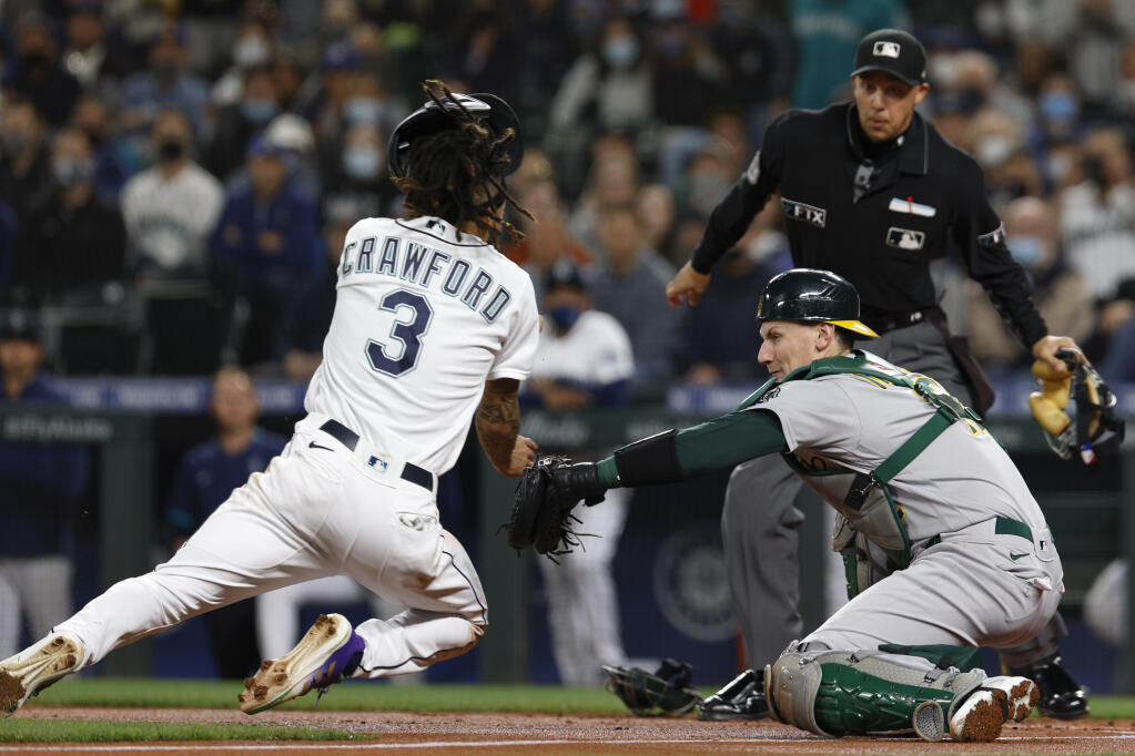 Oakland Athletics catcher Sean Murphy goes for the tag on the Seattle Mariners’ J.P. Crawford for the out at home plate in the first inning on Tuesday, Sept. 28, 2021, in Seattle. (Jason Redmond / ASSOCIATED PRESS)