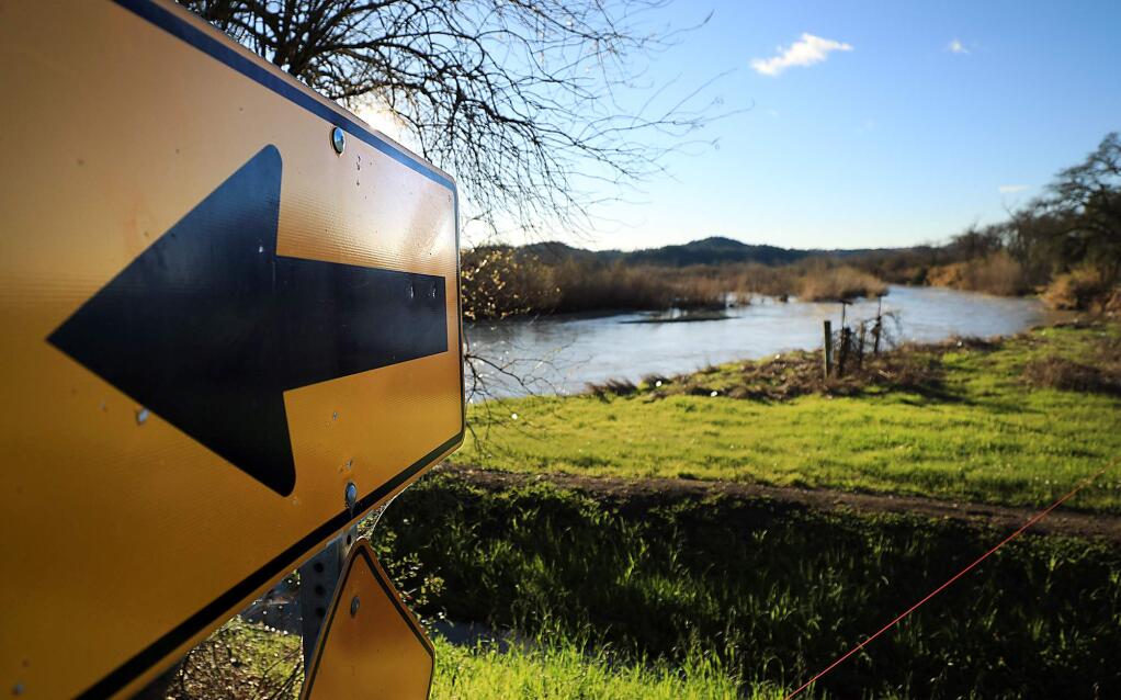 A sign points to a bend in River Road as the Russian River eats away at the east side of the river bank at River Road in Geyserville, Tuesday, Feb. 5, 2019, putting the roadway at risk for collapse. (Kent Porter / The Press Democrat) 2019